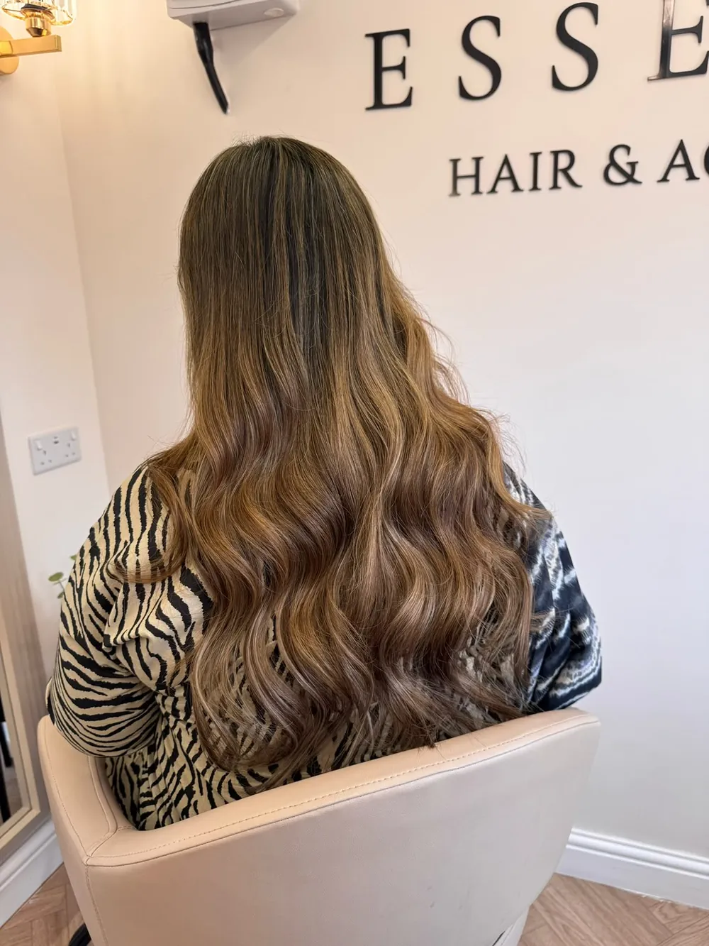 Brunette-to-caramel balayage waves under the Essence Hair & Academy sign