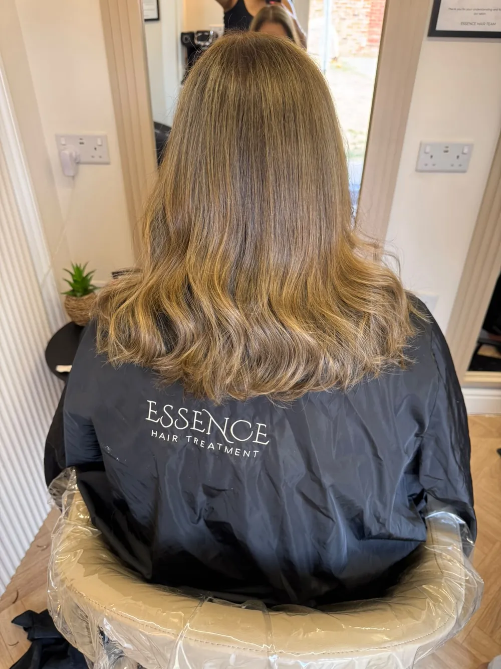 Honey-brown blow-dry with soft, bouncy ends on a client in an Essence gown