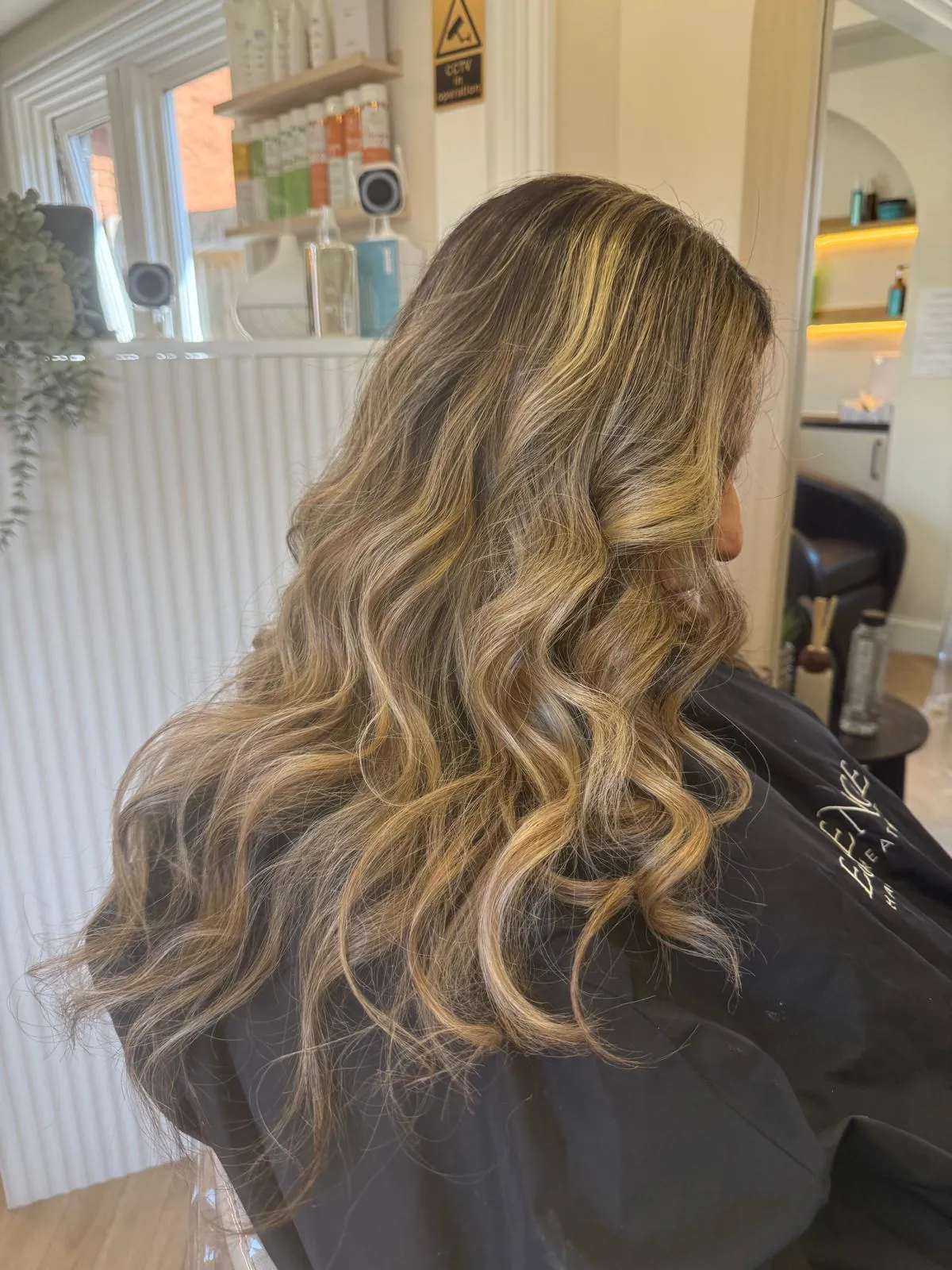 Sun-kissed blonde balayage on long, loose curls
