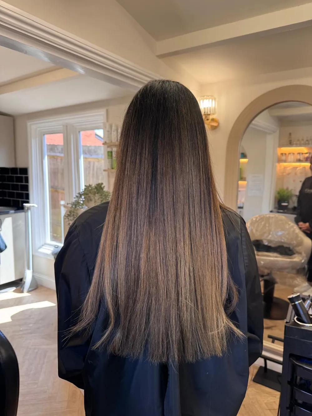 Long straight hair with a brunette-to-caramel balayage blend, back view