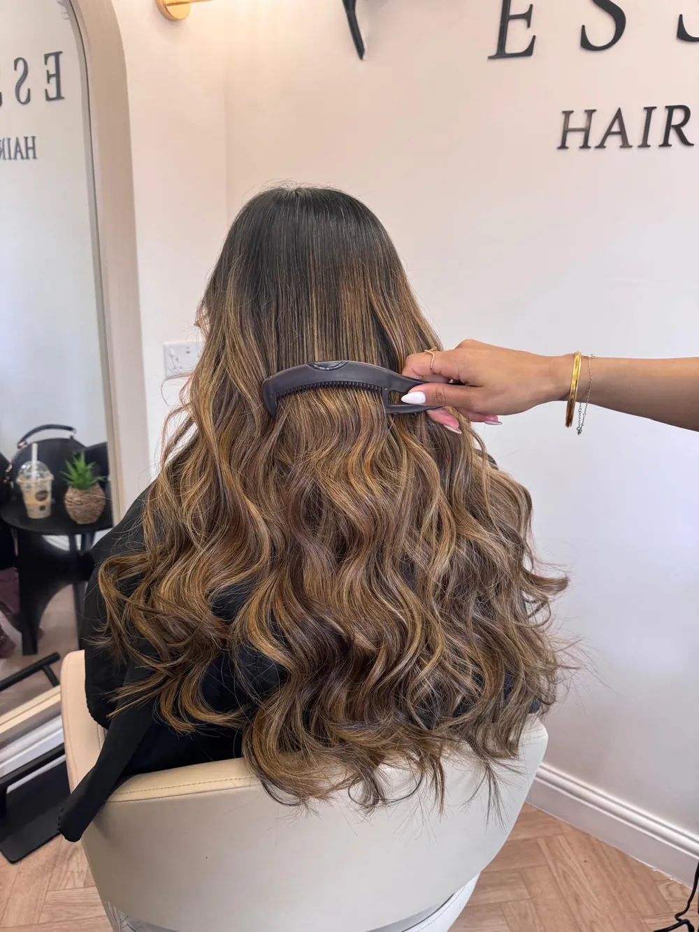 Long brunette hair with caramel balayage and bouncy curls under the Essence sign