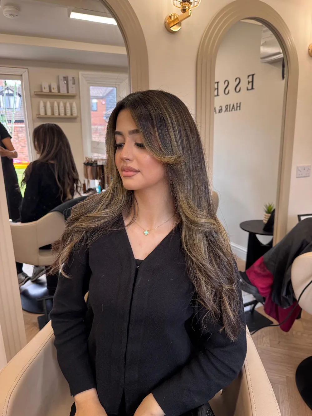 Client with long, layered dark-brown hair and caramel face-framing highlights