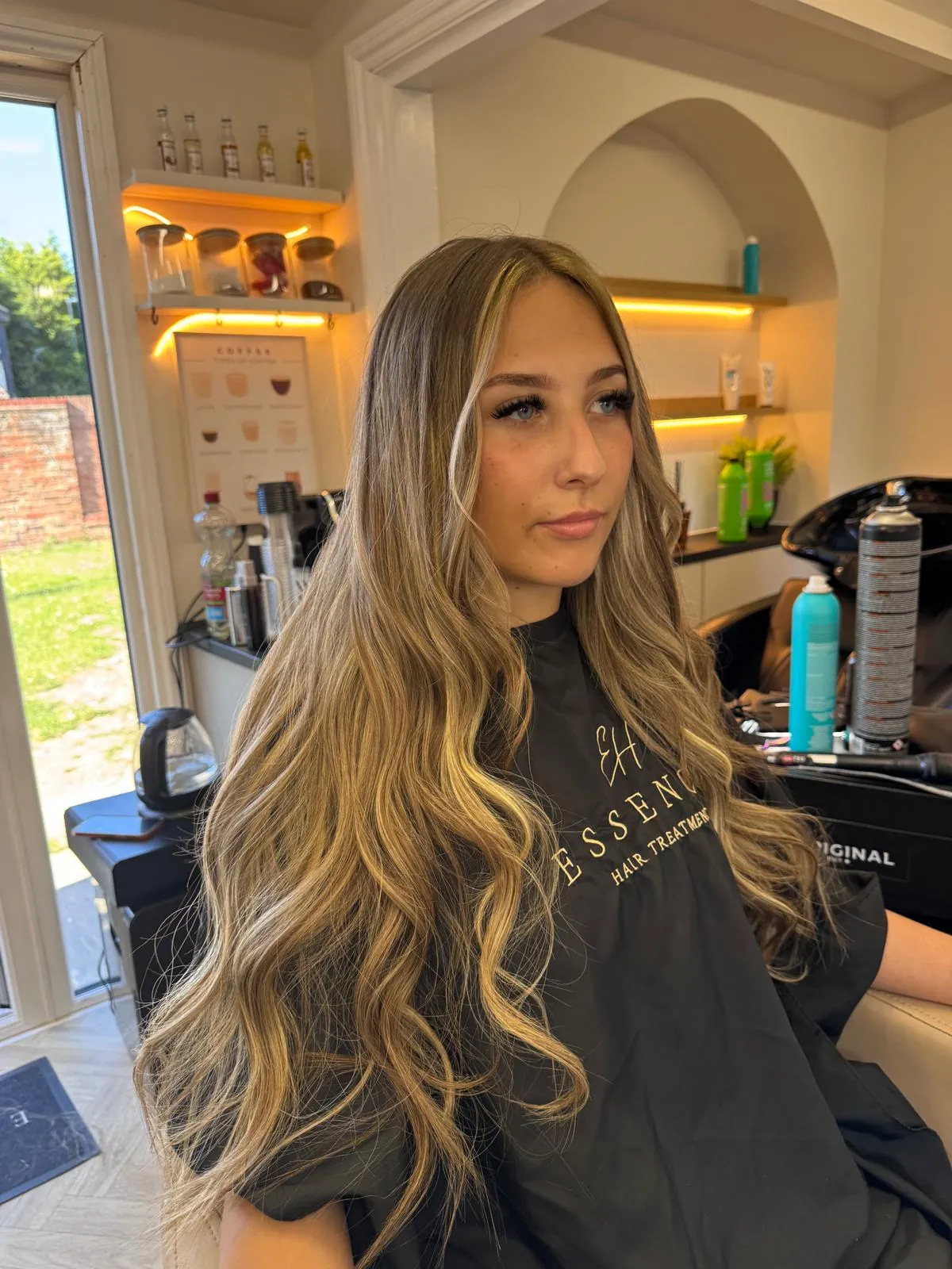 Client with long golden-blonde balayage curls at Essence in Luton